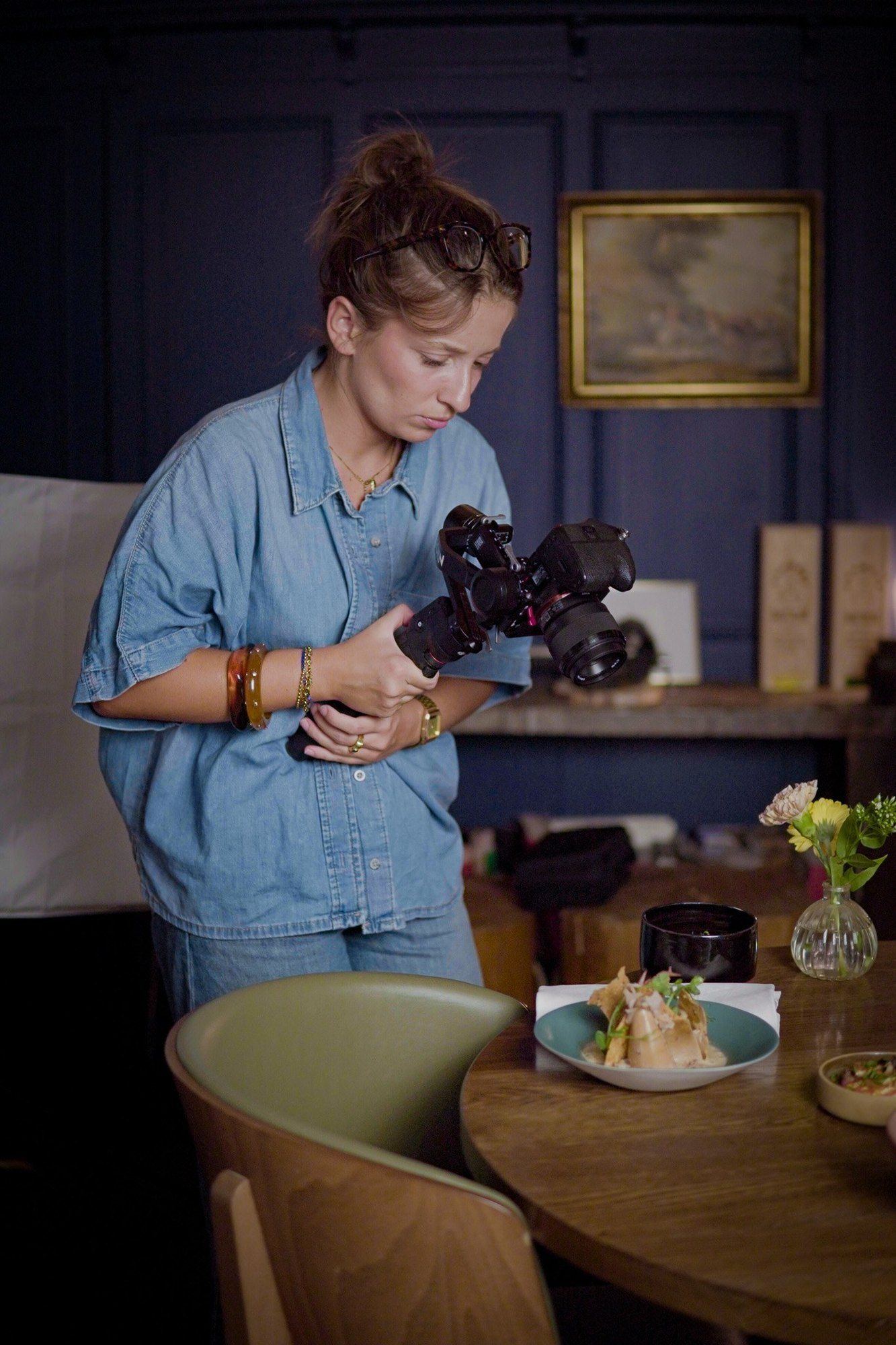 Une photographe de l’équipe cadre un plat sur une table de restaurant, appareil monté sur stabilisateur.