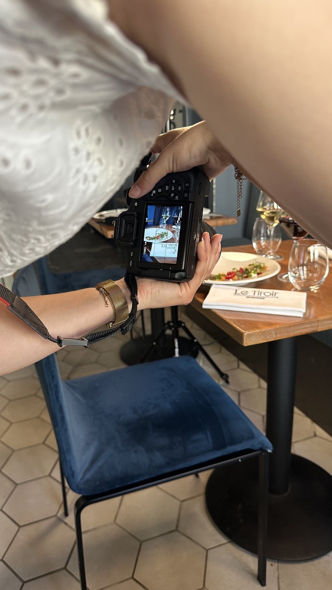 Un appareil photo tenu au-dessus d’une table dressée, en salle de restaurant.